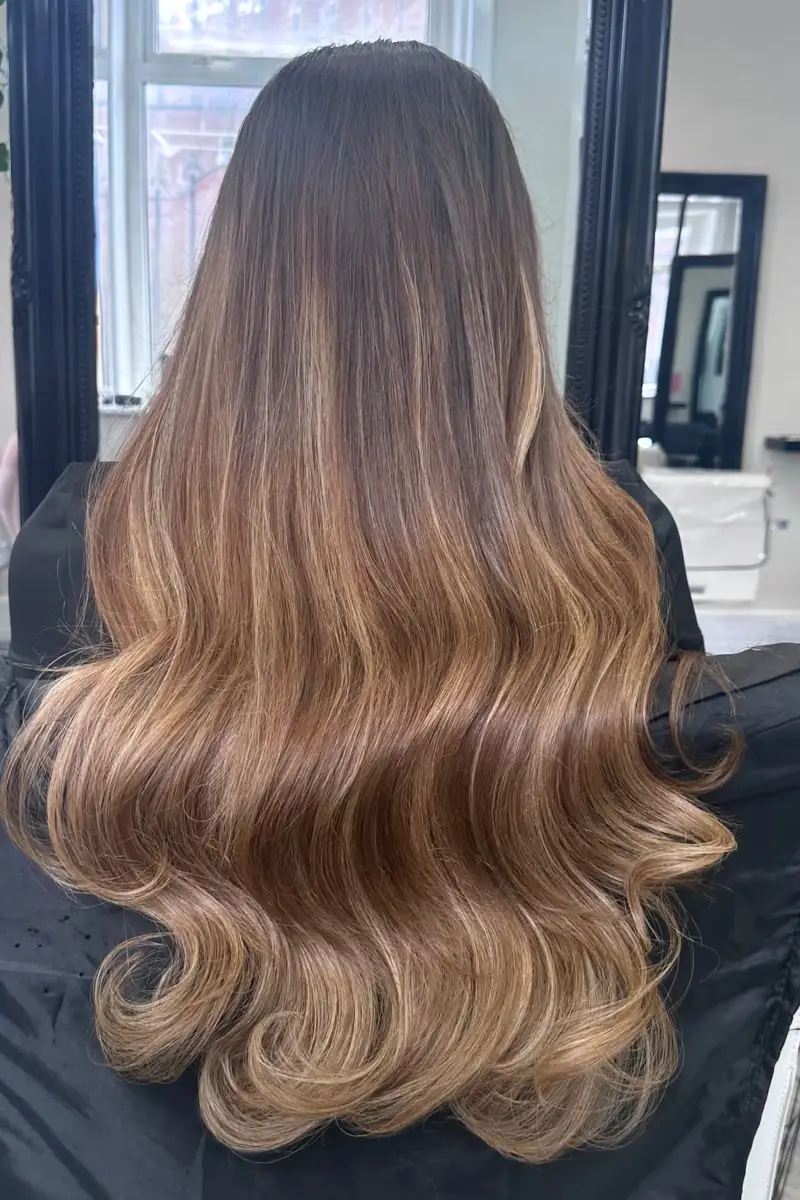 Long, glossy brunette-to-caramel waves finished at Scissorz